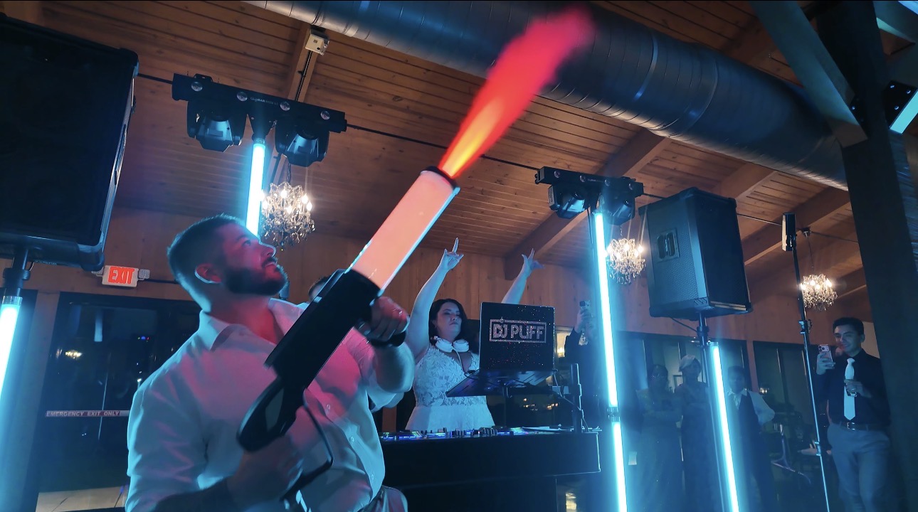 Wedding guest using a CO2 effect with DJ Puff performing behind the booth